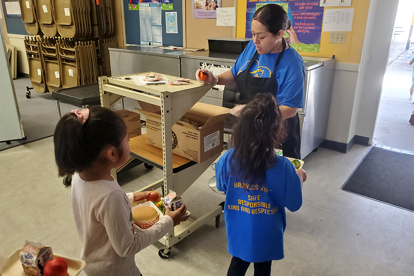 A school nutrition professional uses a tally system as students move quickly through the lunch line